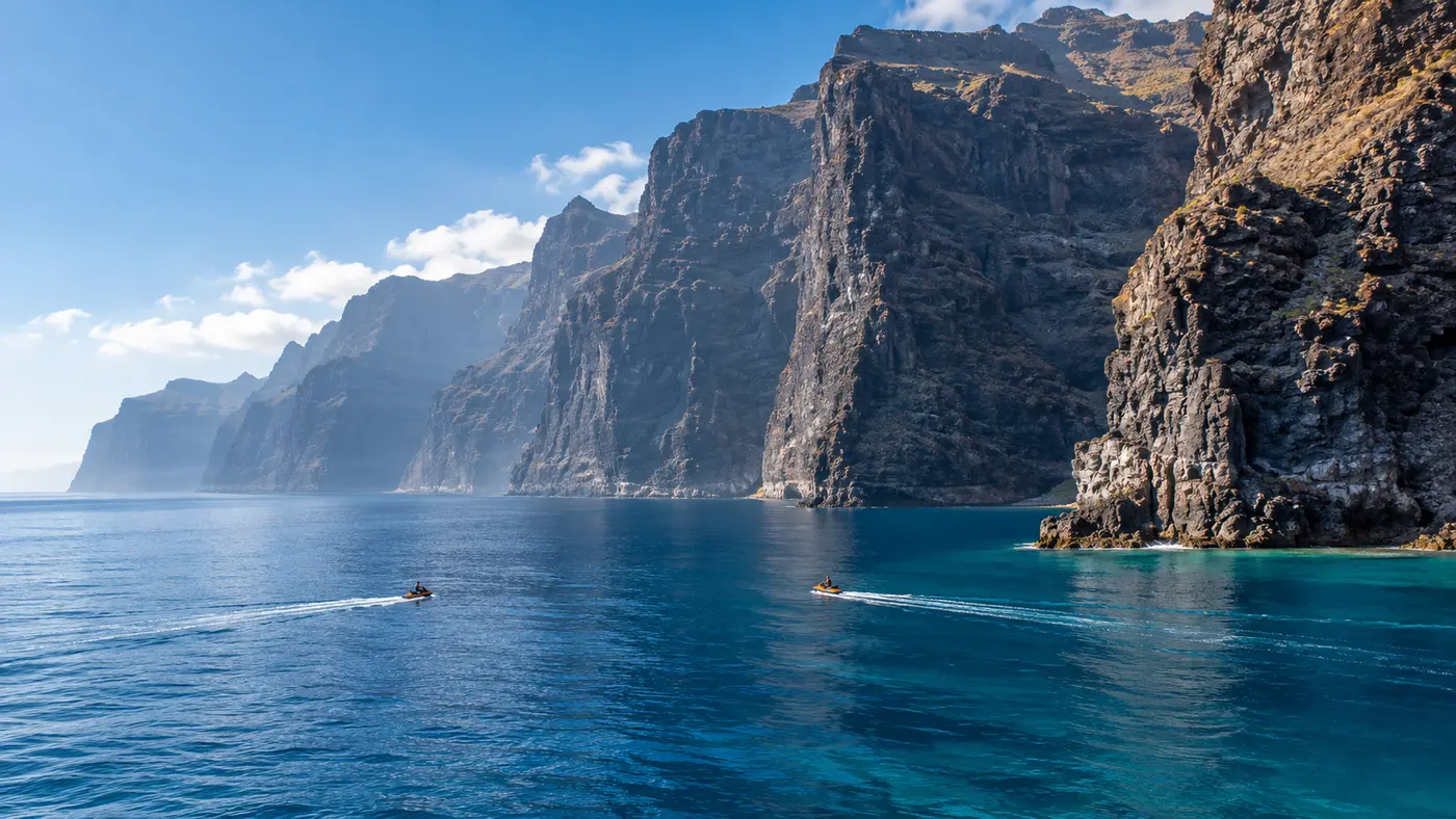 Two jet skis beneath Tenerife's immense volcanic cliffs